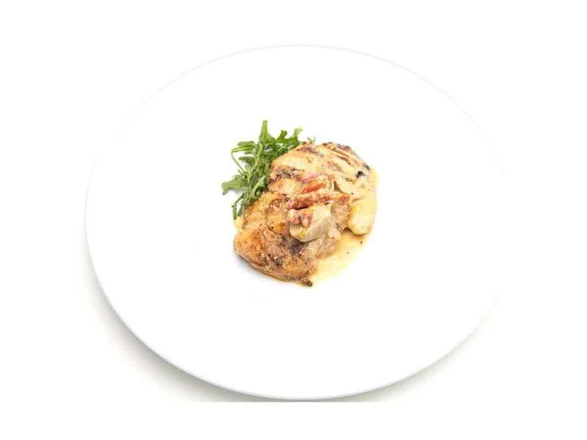 a plate of food on a table Made with grilled chicken breast, sun dried tomatoes, artichokes, white wine, and cream. Gluten Free. Contains Dairy.