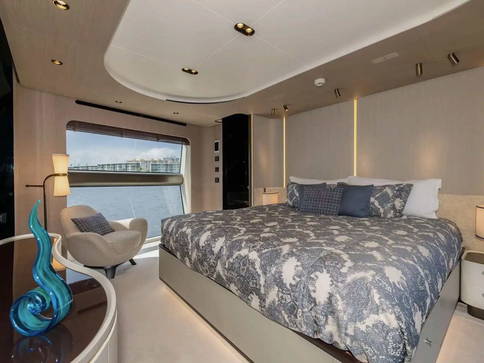 88 Azimut Yacht Charter master stateroom featuring a king-size berth, panoramic waterfront window, elegant lighting, and contemporary luxury interior design in Nassau