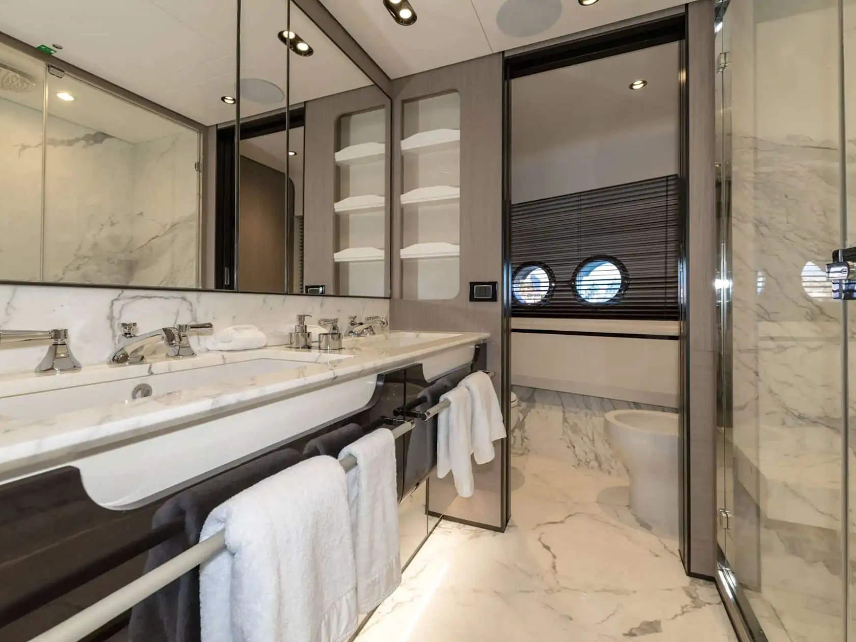 Elegant ensuite bathroom aboard the 88 Azimut Yacht Charter featuring marble finishes, dual vanity sinks, glass shower enclosure, and luxury interior accommodations in Nassau, Bahamas.