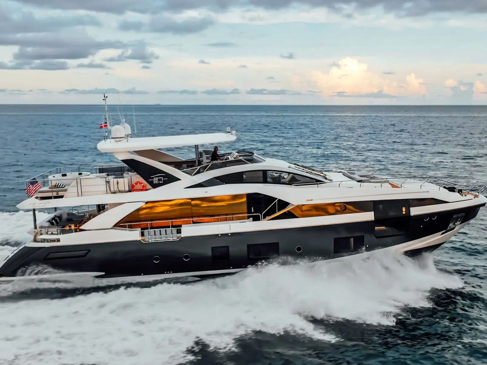Spectacular 88 Azimut Yacht Charter cruising through turquoise Bahamian waters near Nassau, featuring a sleek profile, panoramic windows, and luxury yachting performance at sea.
