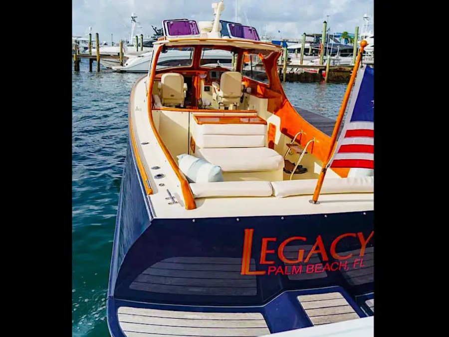The 36 foot Hinckley Picnic Boat Boat Rental showcases an elegant aft cockpit with cushioned seating, handcrafted wood trim, and classic maritime styling while docked on Palm Beach waterways.