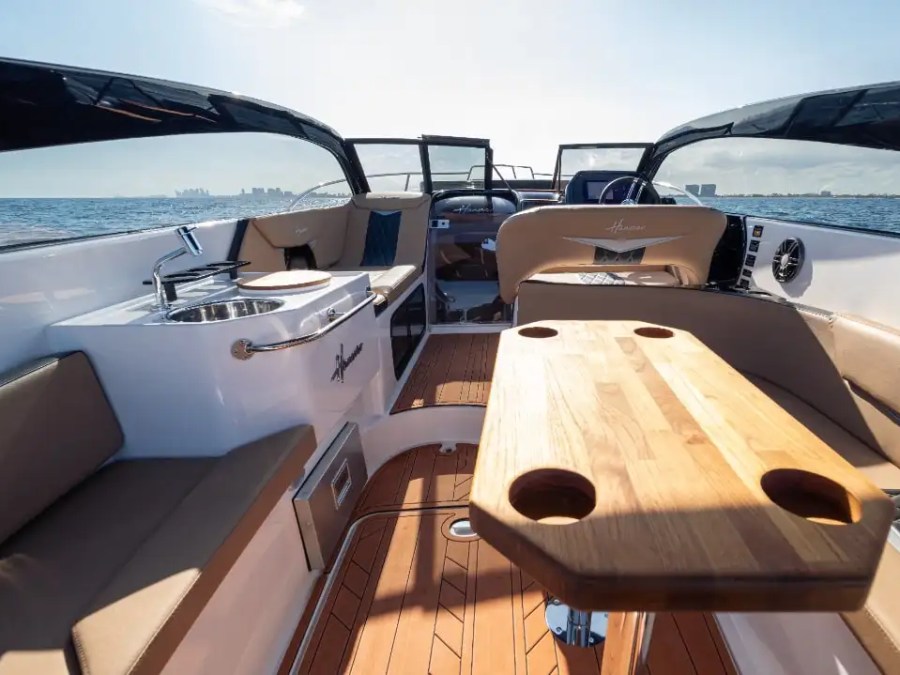 The cockpit lounge aboard this 33 foot Hanover Boat Rental features wraparound seating, a wood table, and open-water views during a Palm Beach Boat Rental.