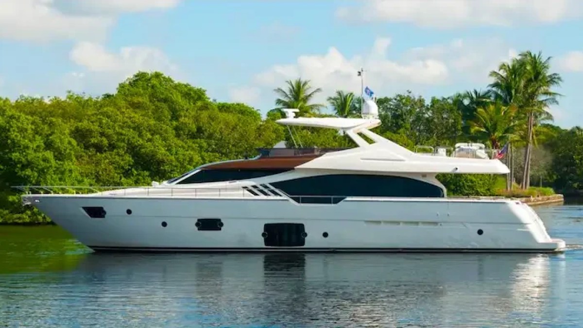 The 88′ Ferretti yacht cruises through calm tropical waters surrounded by lush mangroves and palm-lined shoreline scenery in the Bahamas.
