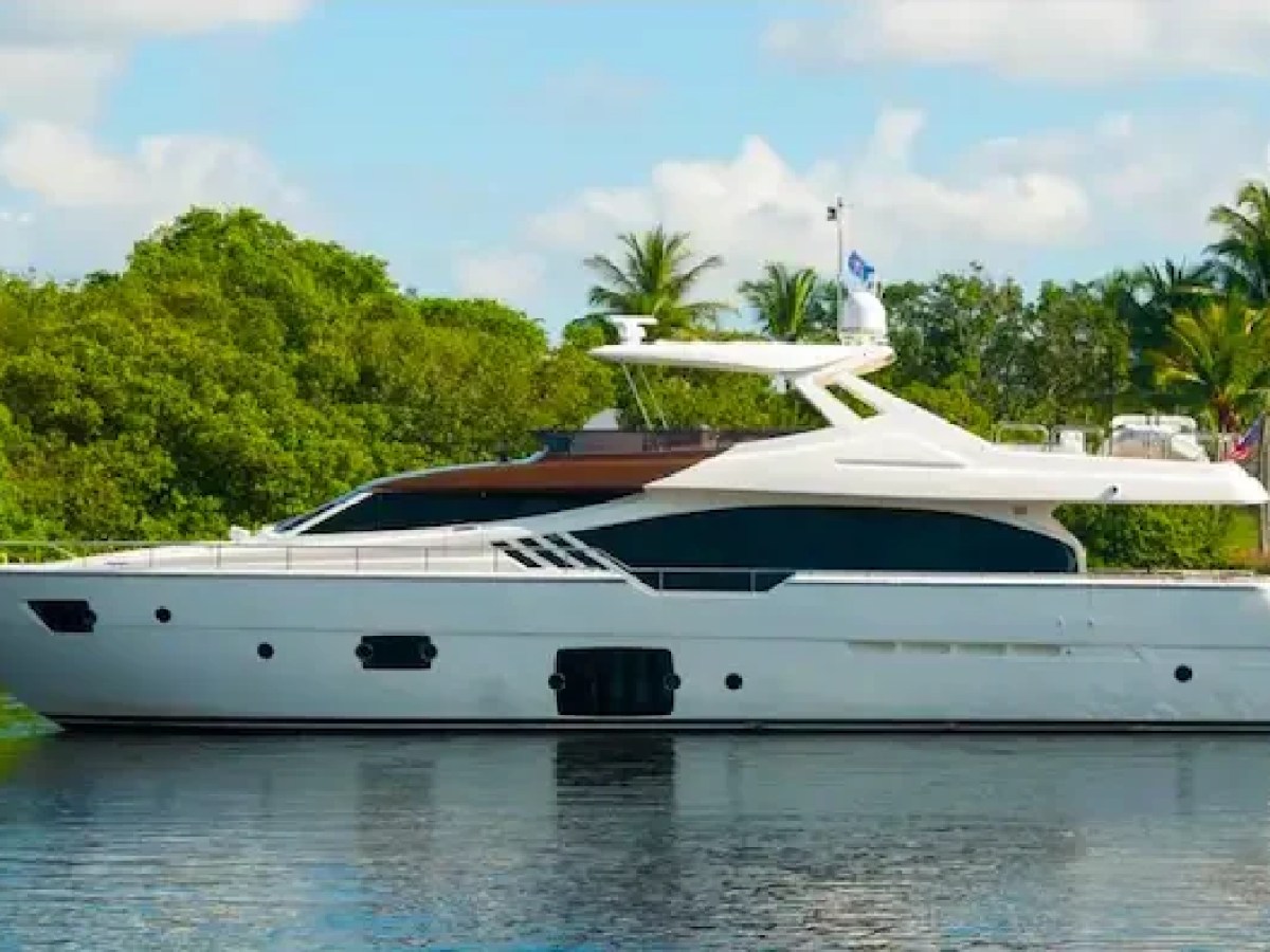 The 88′ Ferretti yacht cruises through calm tropical waters surrounded by lush mangroves and palm-lined shoreline scenery in the Bahamas.