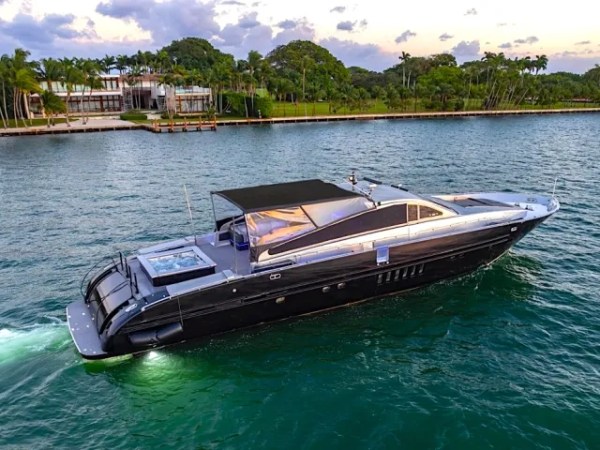 94 Leopard Yacht Charter cruising along Miami waterfront with sleek black hull, retractable shade canopy, and luxury sport yacht styling near Venetian Islands
