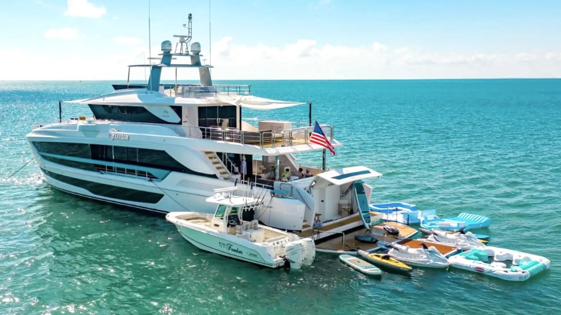 110 foot Horizon Yacht Charter anchored in turquoise waters off Fort Lauderdale with tender boat, water toys, floating lounge platforms, and luxury yacht charter amenities visible in South Florida.