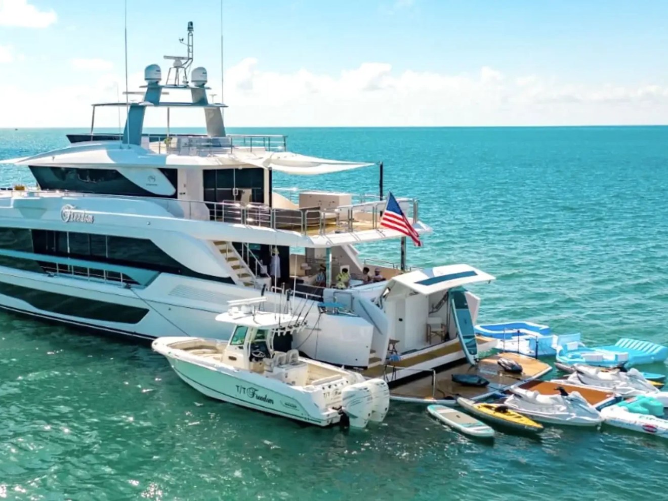 110 foot Horizon Yacht Charter anchored in turquoise waters off Fort Lauderdale with tender boat, water toys, floating lounge platforms, and luxury yacht charter amenities visible in South Florida.