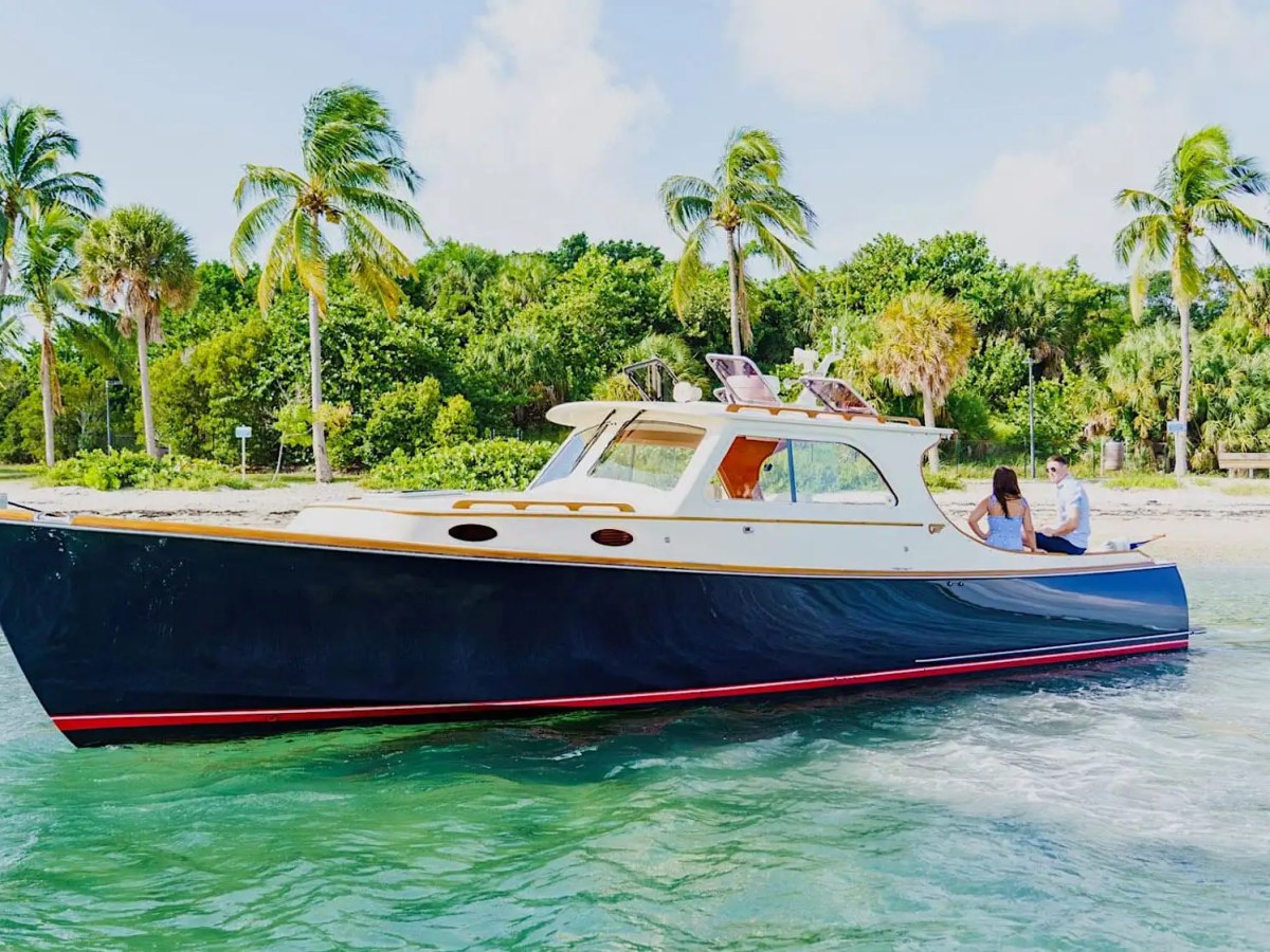 This 36 foot Hinckley Picnic Boat Boat Rental cruises the tropical shoreline of Riviera Beach with classic Downeast styling, handcrafted detailing, and clear South Florida waters in the background.