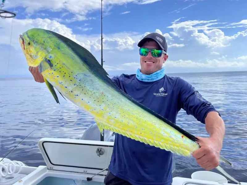 Angler displaying a freshly caught mahi-mahi aboard a 26' PowerCat Boat Rental in Marathon, showcasing Florida Keys offshore fishing on calm Gulf of America waters.