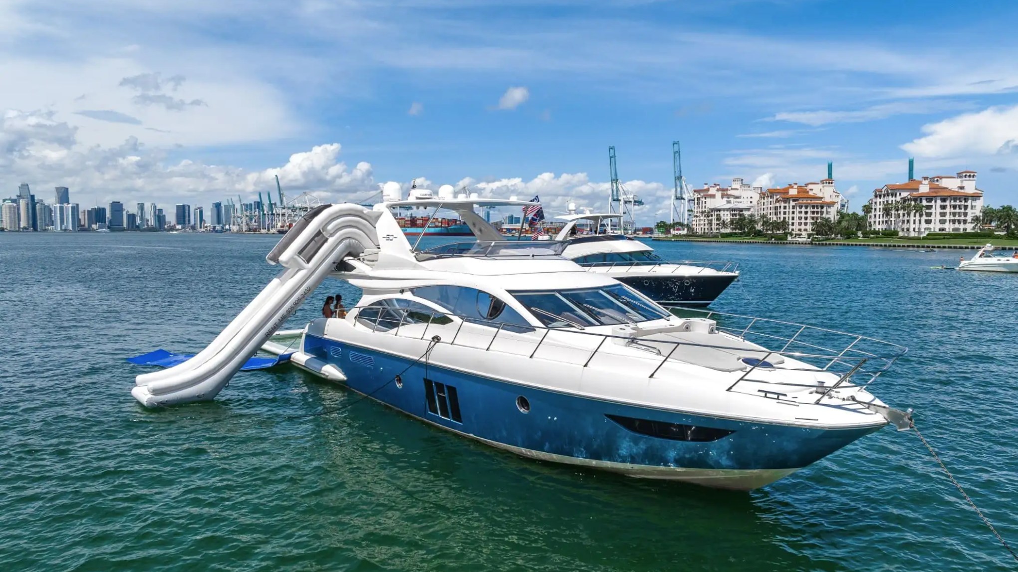 Giant inflatable slide extended behind 62′ Azimut luxury yacht rental at anchor
