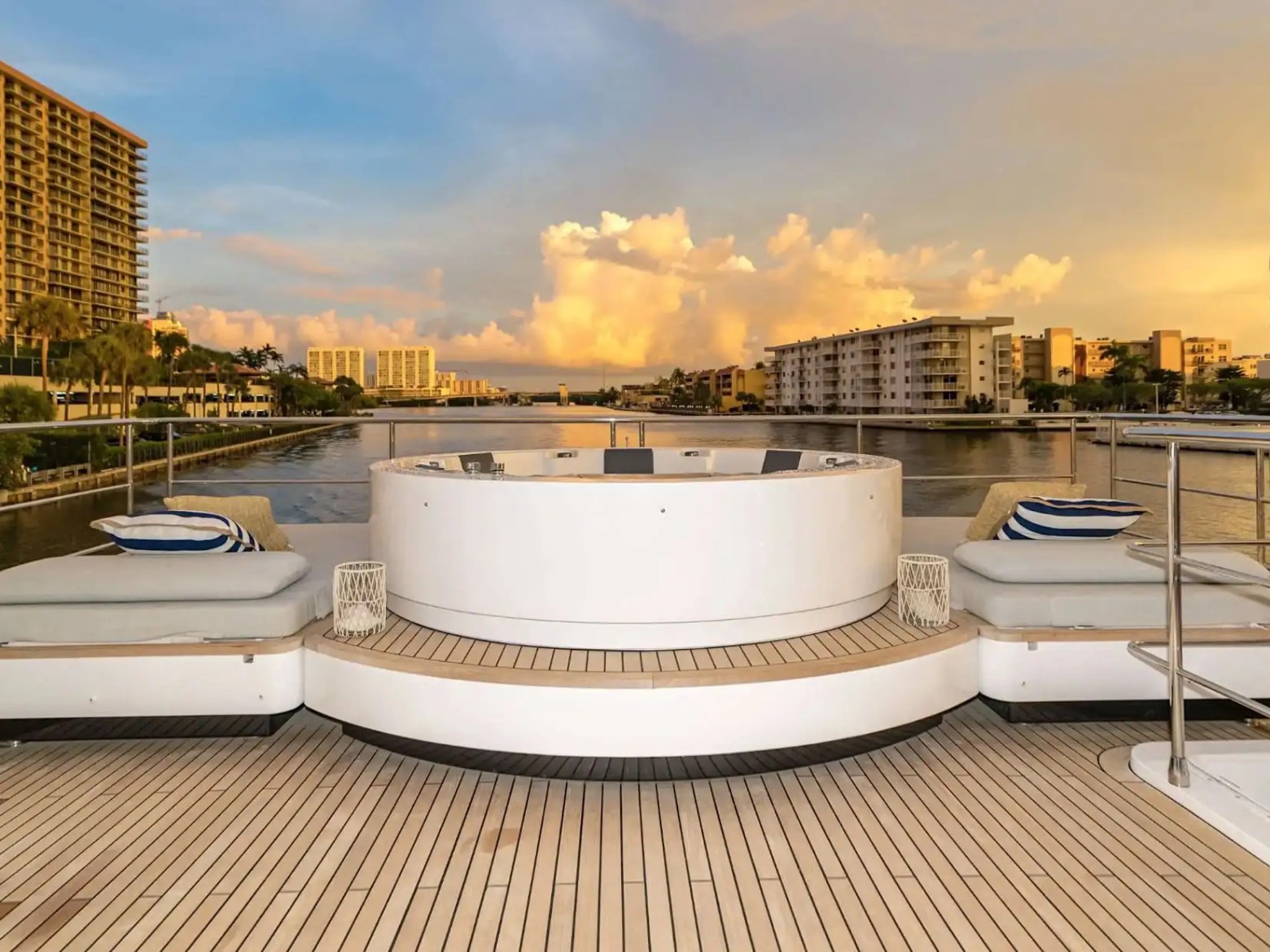 88 Azimut Yacht Charter aft deck jacuzzi overlooking Nassau waterfront canal at sunset, featuring cushioned lounge seating and scenic Bahamas waterway views