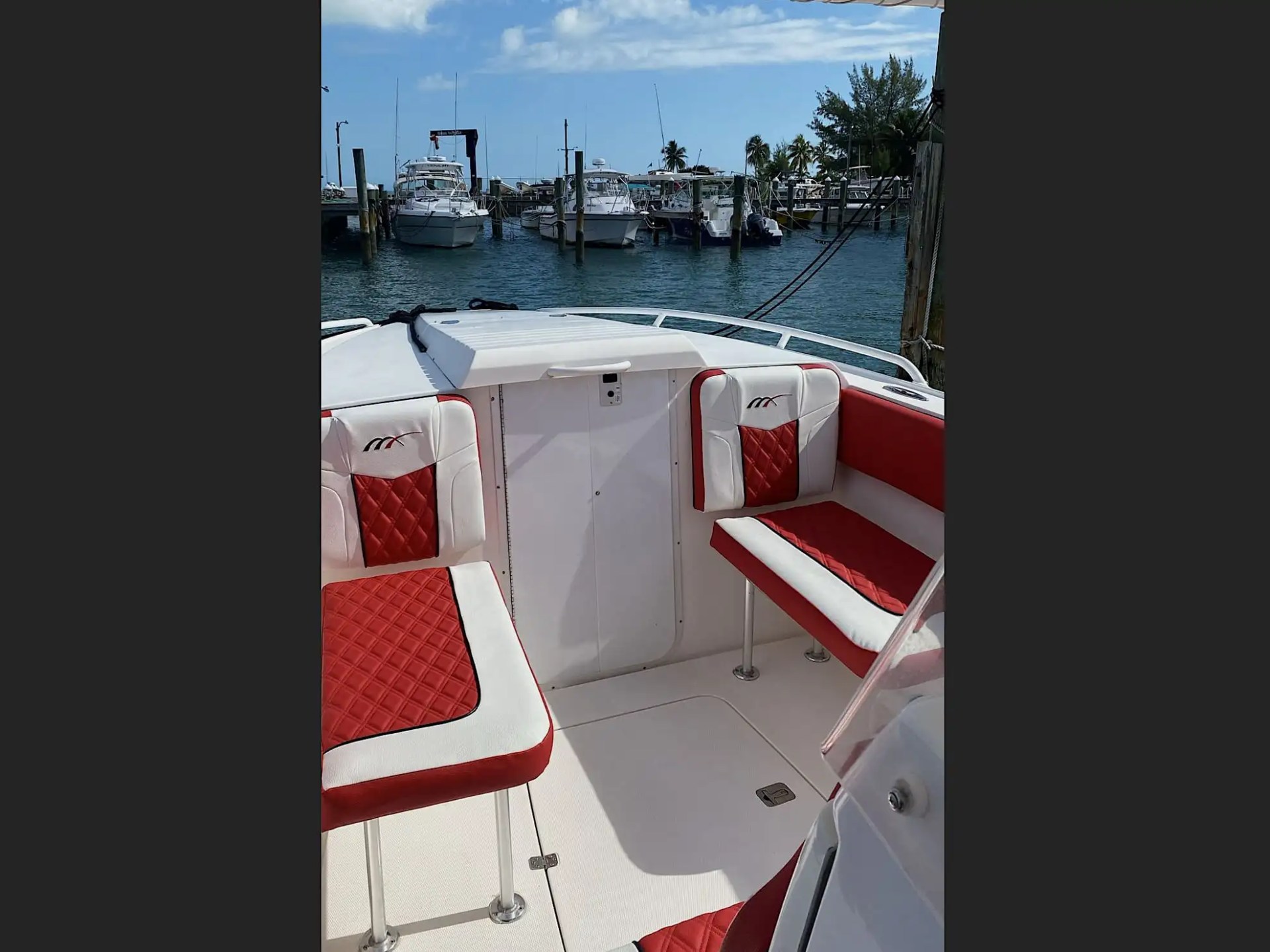 35' Marlin Boat Rental forward seating area with custom red-and-white diamond-stitched cushions docked at a Nassau marina, showcasing comfortable bow lounge space for Bahamas cruising.