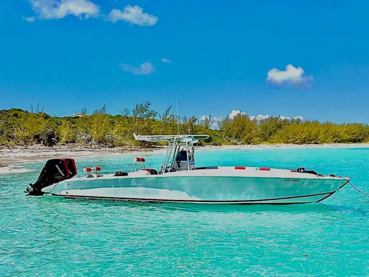 35' Marlin Boat Rental anchored in shallow turquoise waters near a secluded Nassau Bahamas beach, showcasing the sleek center console design, tropical shoreline, and crystal-clear Caribbean conditions.