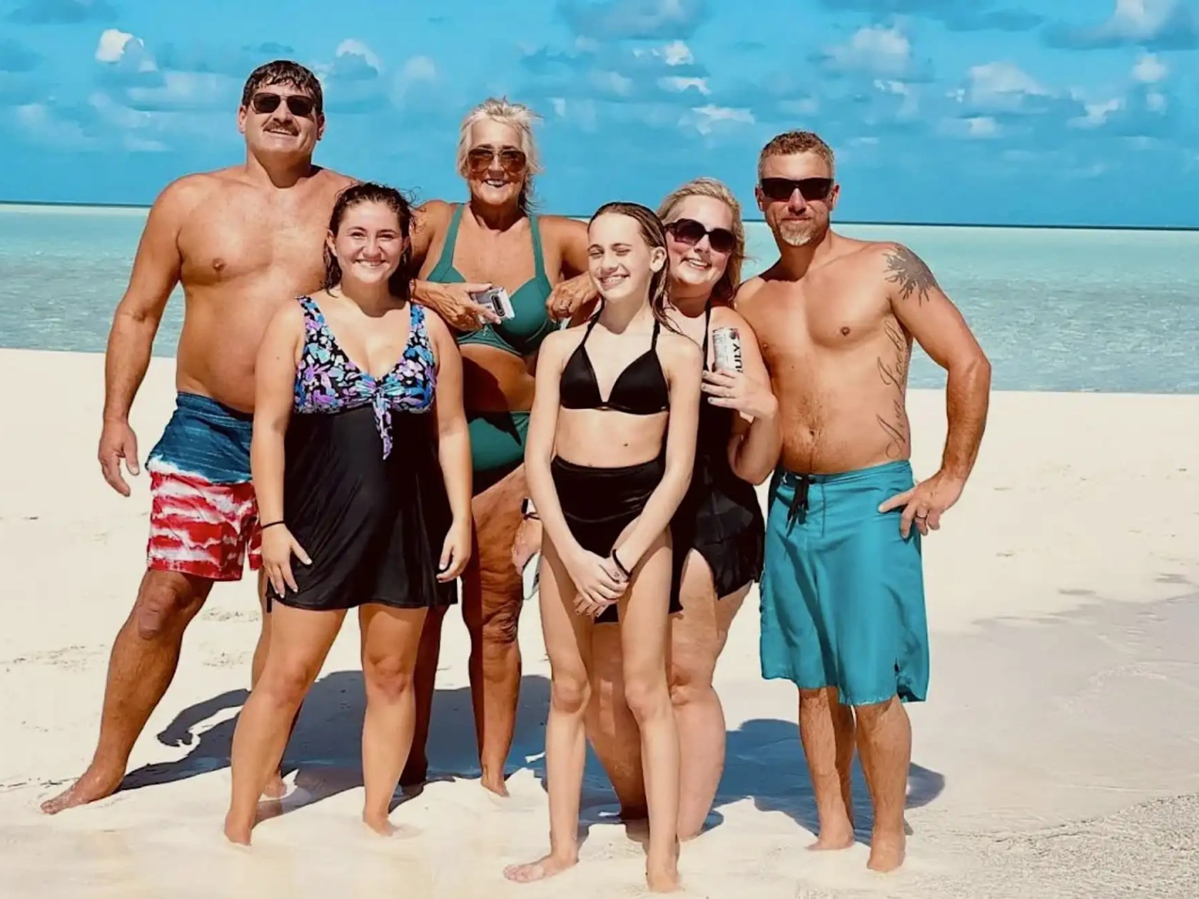 Family enjoying a pristine white sand beach during a 35' Marlin Boat Rental excursion in Nassau, Bahamas, surrounded by shallow turquoise waters and a peaceful tropical island setting.