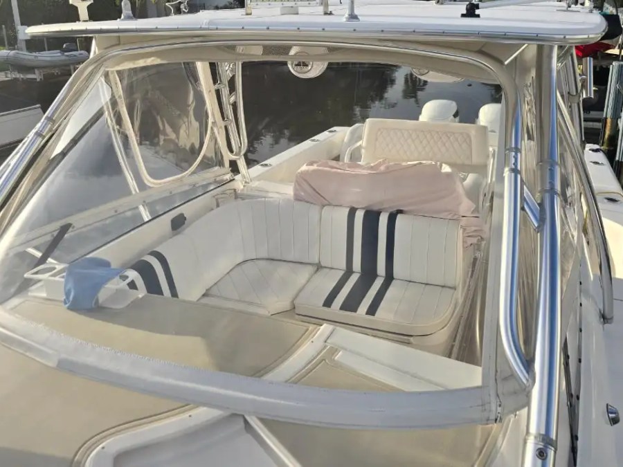 37 foot Intrepid center console boat rental featuring cushioned forward seating beneath the hardtop in Pompano Beach, Florida with wraparound lounge seating and polished stainless framing visible.