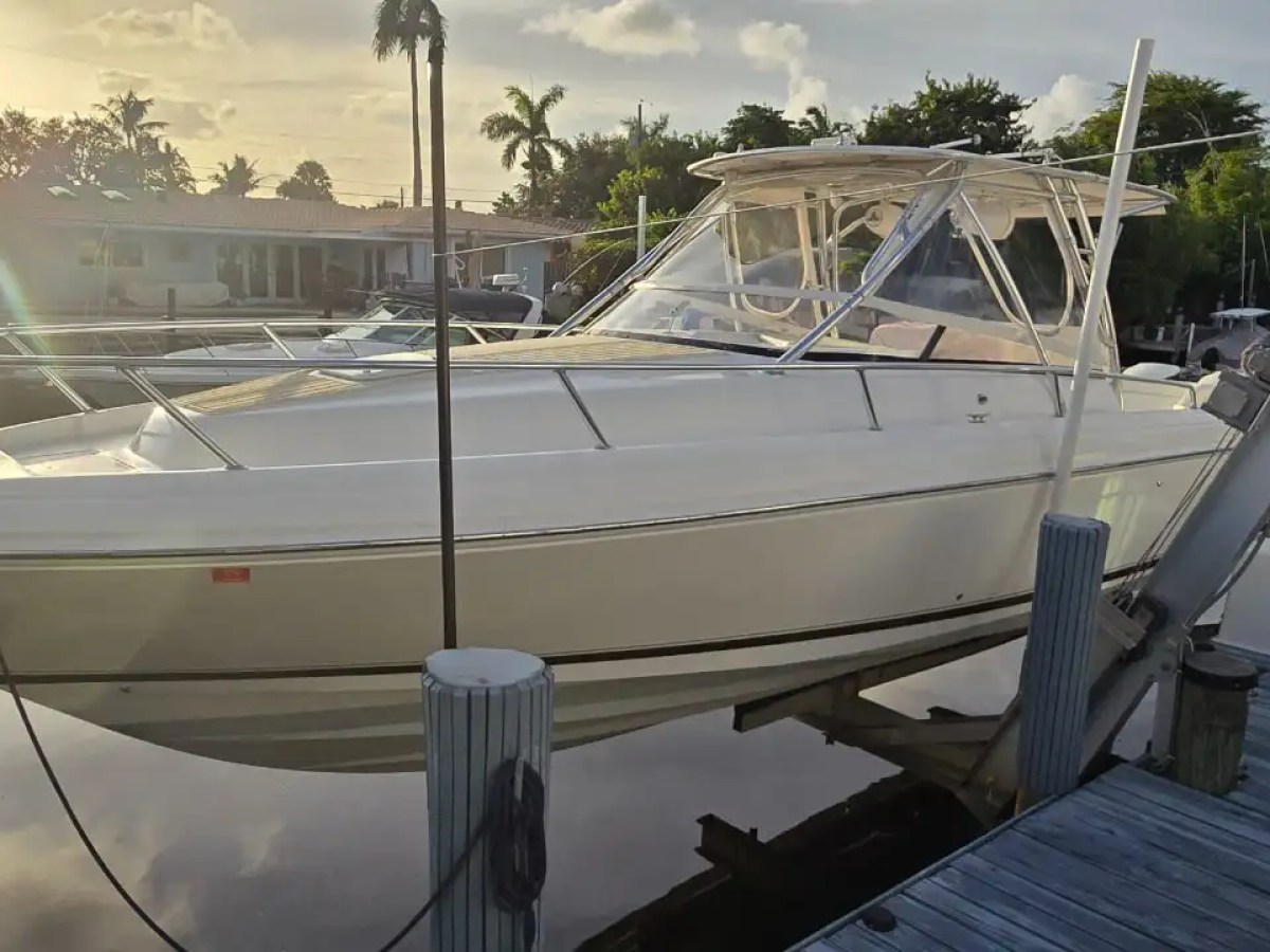 37 foot Intrepid center console boat rental docked along a residential waterfront canal in Pompano Beach, Florida with sleek walkaround design, hardtop helm, and open bow seating visible.