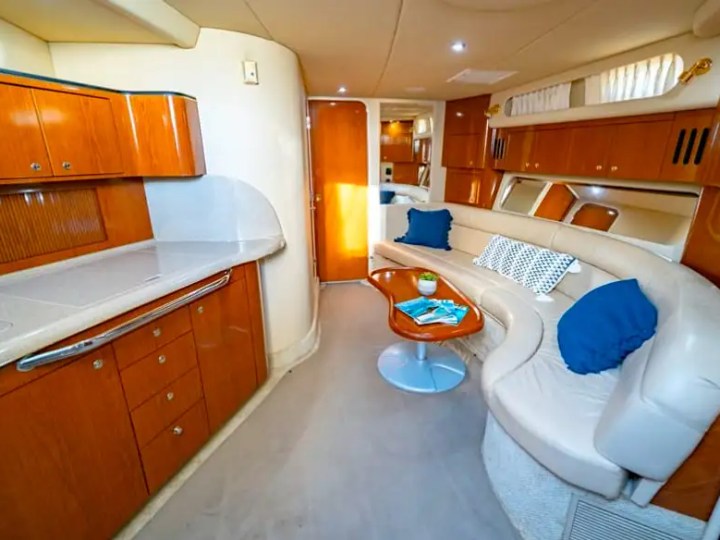 45 foot SeaRay Boat Rental salon in Hollywood, Florida featuring curved leather seating, rich wood cabinetry, and comfortable indoor living space for a relaxing South Florida Boat Rental experience.