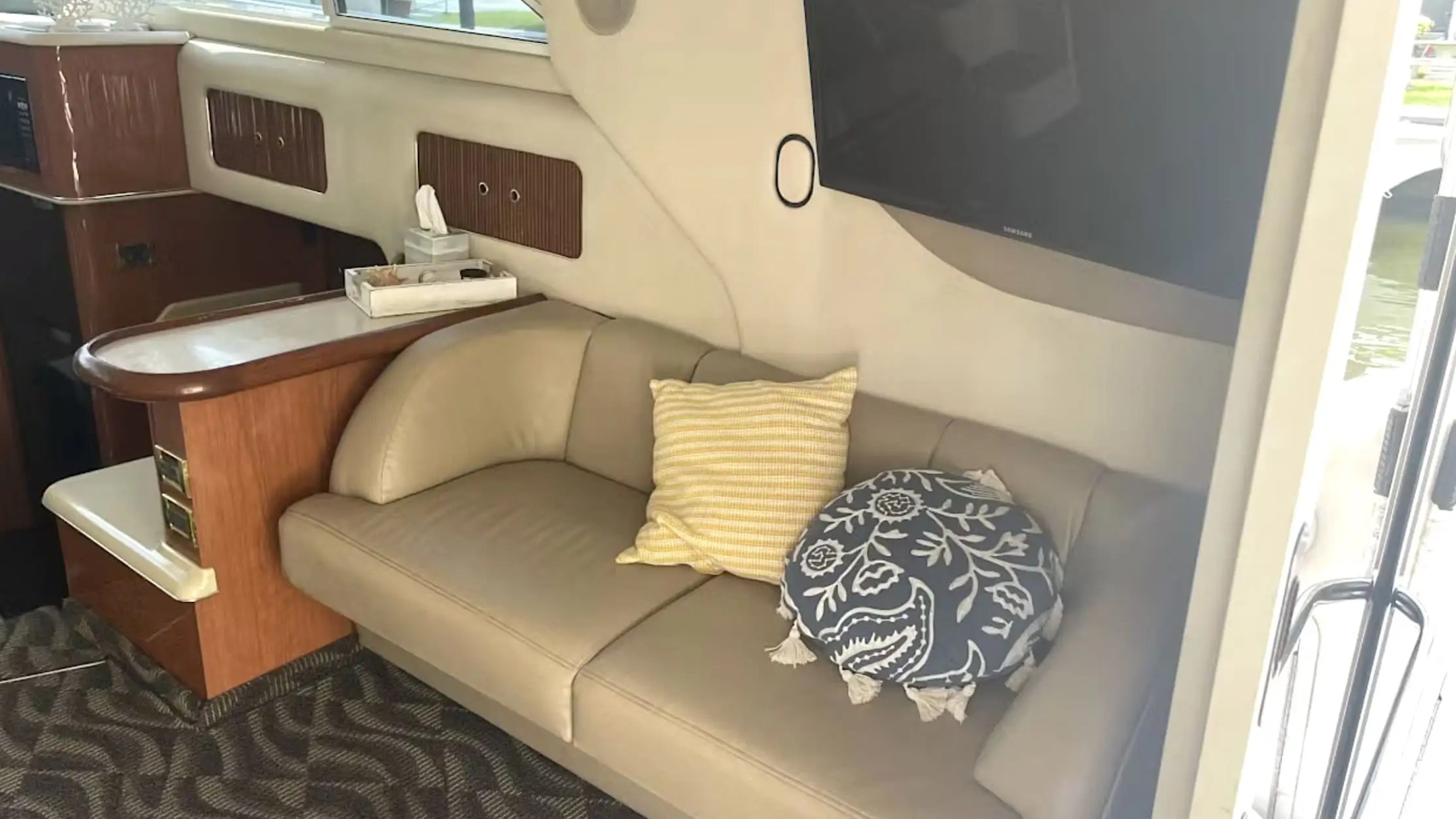40' SeaRay - Boat Rental in Fort Lauderdale, Floridae couch, yellow and blue pillows, TV, and wooden cabinetry.