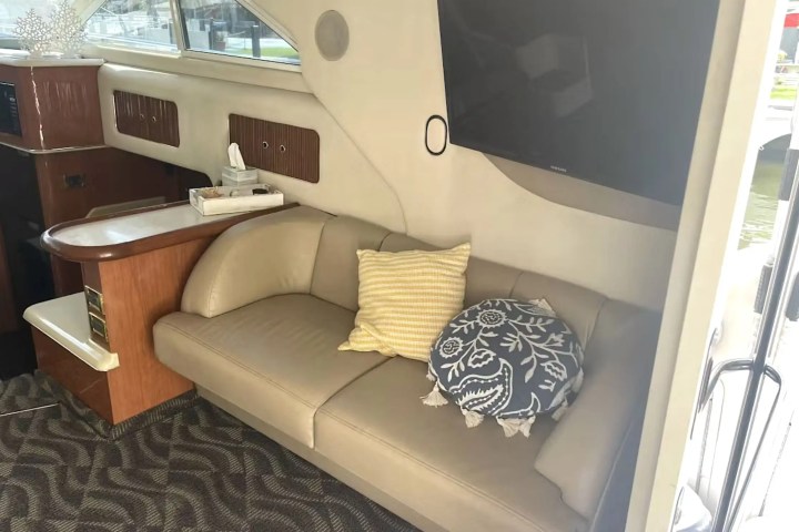 40' SeaRay - Boat Rental in Fort Lauderdale, Floridae couch, yellow and blue pillows, TV, and wooden cabinetry.