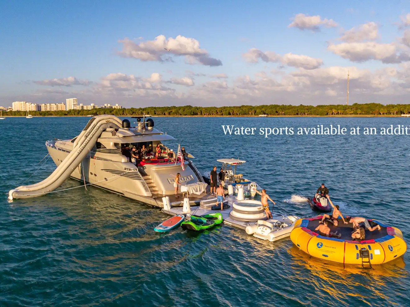 90 Pershing Yacht Charter anchored near Virginia Key with inflatable slide, floating trampoline, jet ski, paddleboard, and guests enjoying Miami waters
