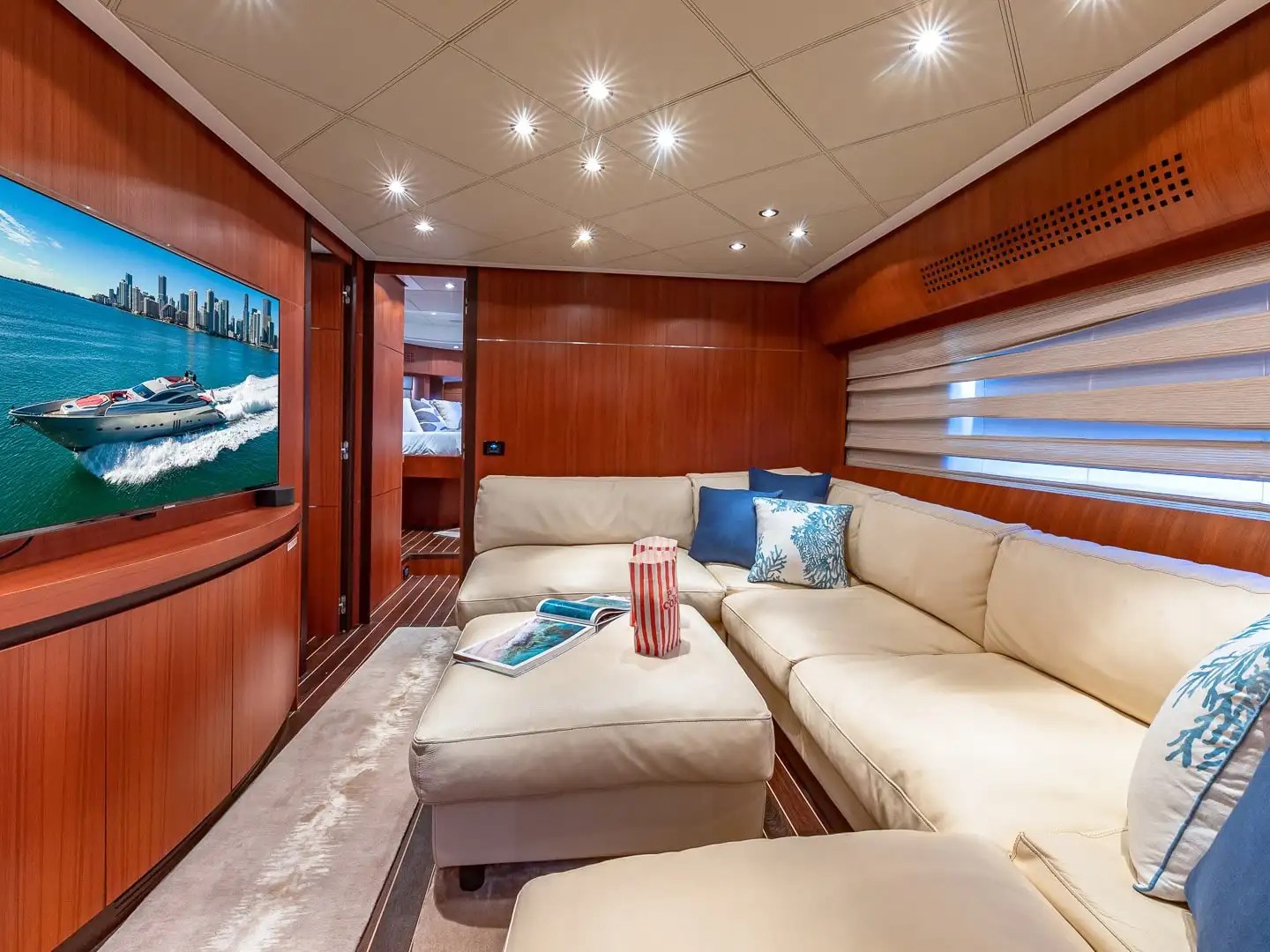 90 Pershing Yacht Charter media lounge featuring cream sectional seating, wood-paneled interior, entertainment center, and luxury Miami yacht accommodations
