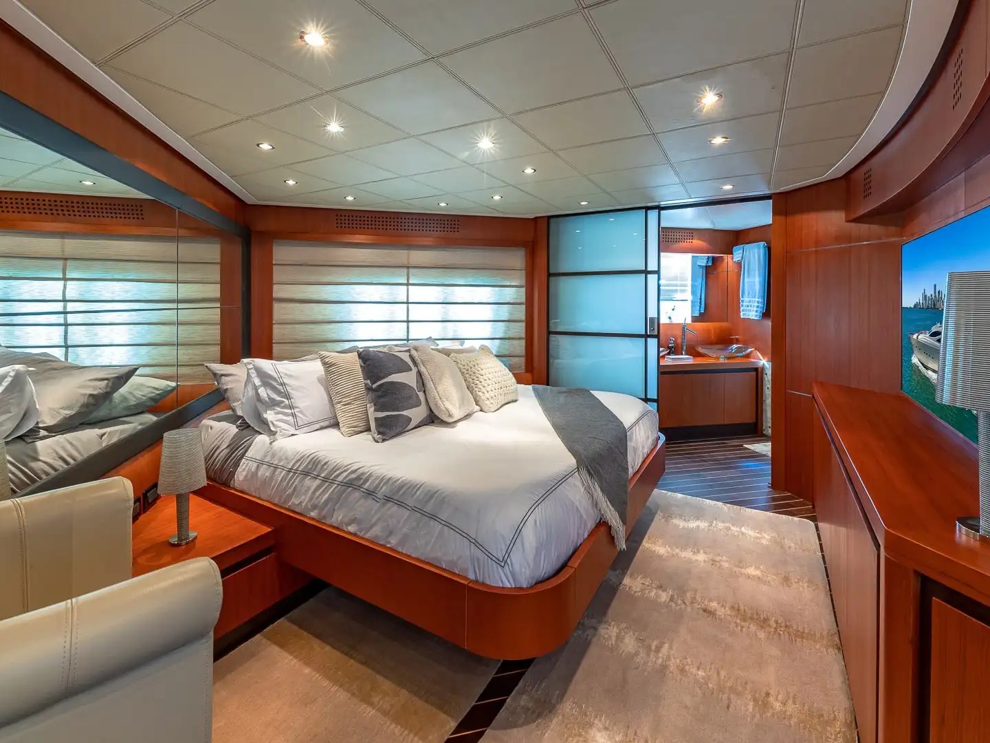 90 Pershing Yacht Charter master stateroom featuring a queen berth, wood-paneled interior, ensuite entrance, and elegant accommodations for Miami yacht cruising