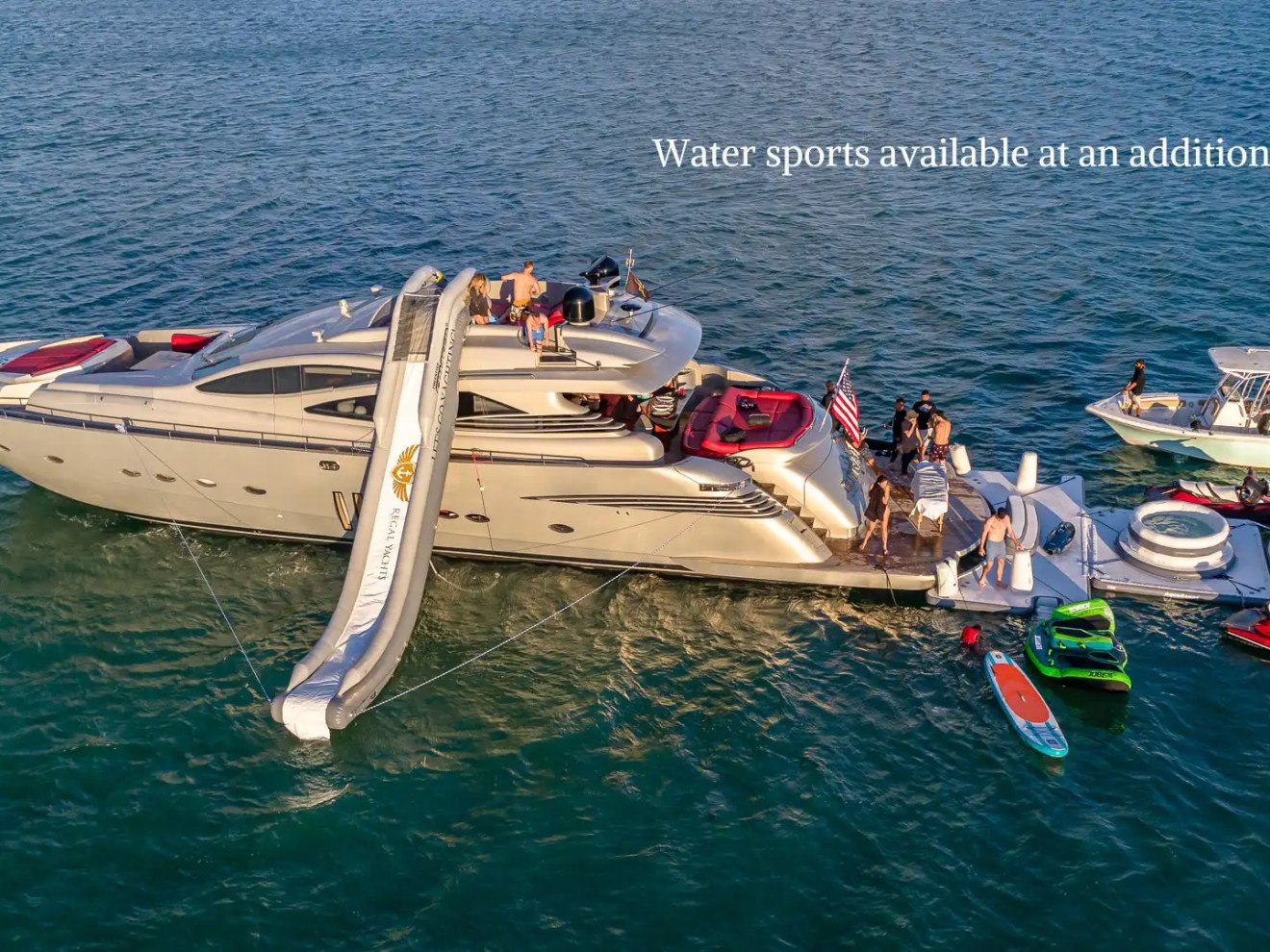 90 Pershing Yacht Charter aerial view anchored off Fisher Island with inflatable slide, jet skis, paddleboard, floating platform, and guests enjoying South Florida waters