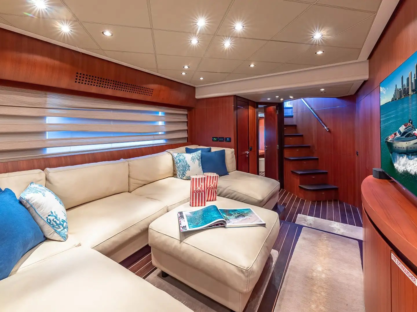 90 Pershing Yacht Charter entertainment lounge featuring cream sectional seating, wood-paneled interior, media center, and luxury accommodations for Miami yacht cruising