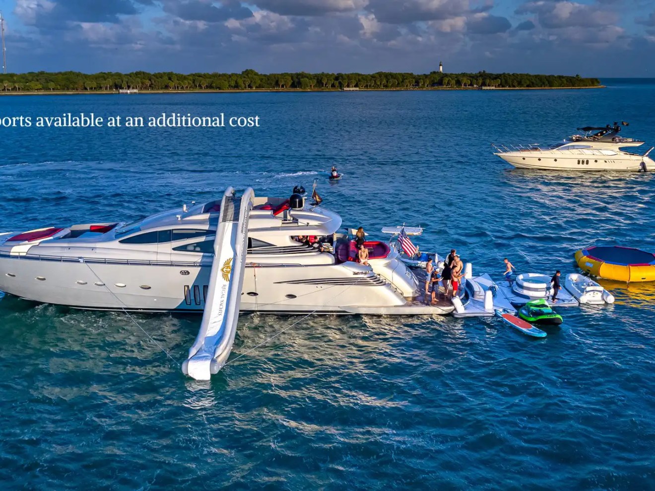90 Pershing Yacht Charter anchored near Key Biscayne with inflatable slide, floating water toys, paddleboard, and guests enjoying South Florida waters
