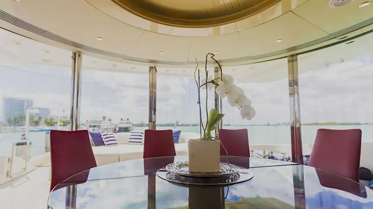 Elegant round table with orchid vase in yacht dining area overlooking water.