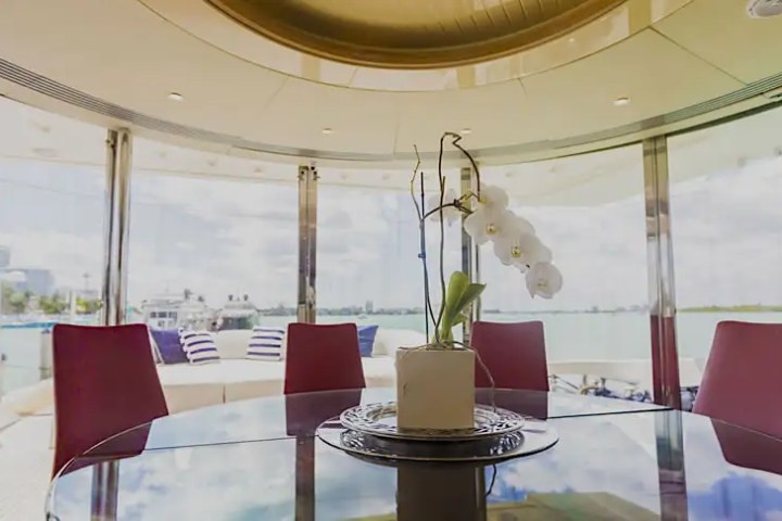 Elegant round table with orchid vase in yacht dining area overlooking water.