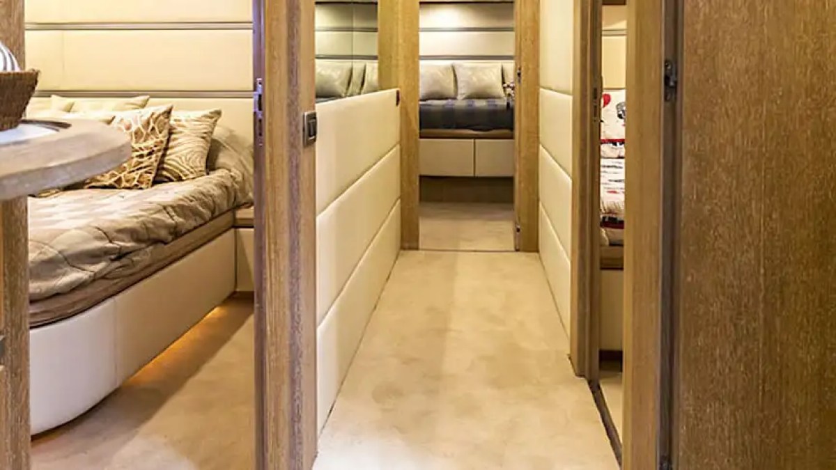 Narrow hallway in a yacht with open doors to bedrooms on both sides.