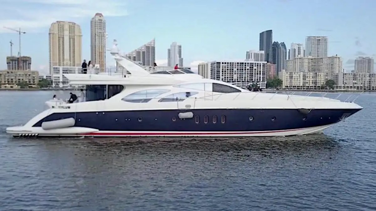 Luxury yacht sailing near a city skyline on a clear day.