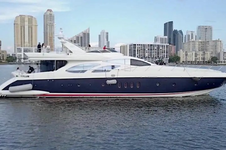 Luxury yacht sailing near a city skyline on a clear day.