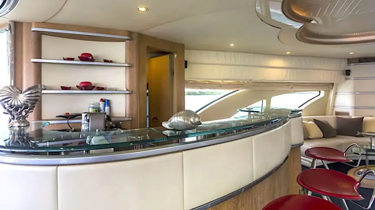 Luxurious yacht interior with curved bar, red stools, and modern decor.