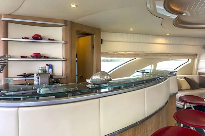 Luxurious yacht interior with curved bar, red stools, and modern decor.