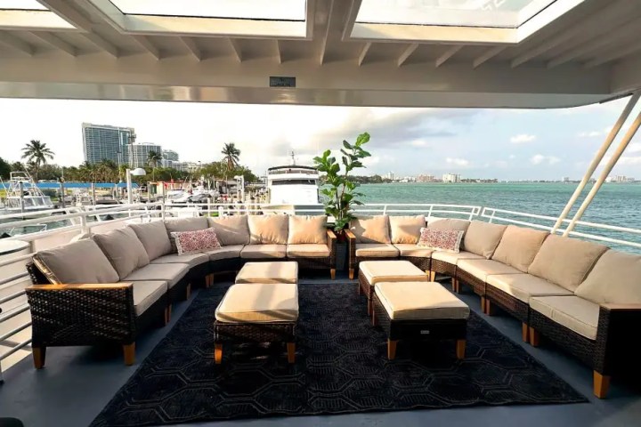 Spacious boat deck with U-shaped sofa, center tables, and sea view.