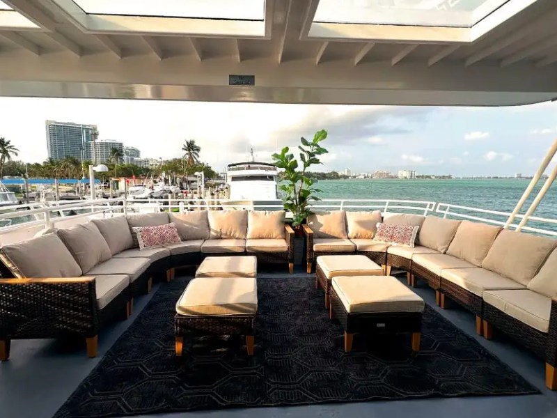 Spacious boat deck with U-shaped sofa, center tables, and sea view.
