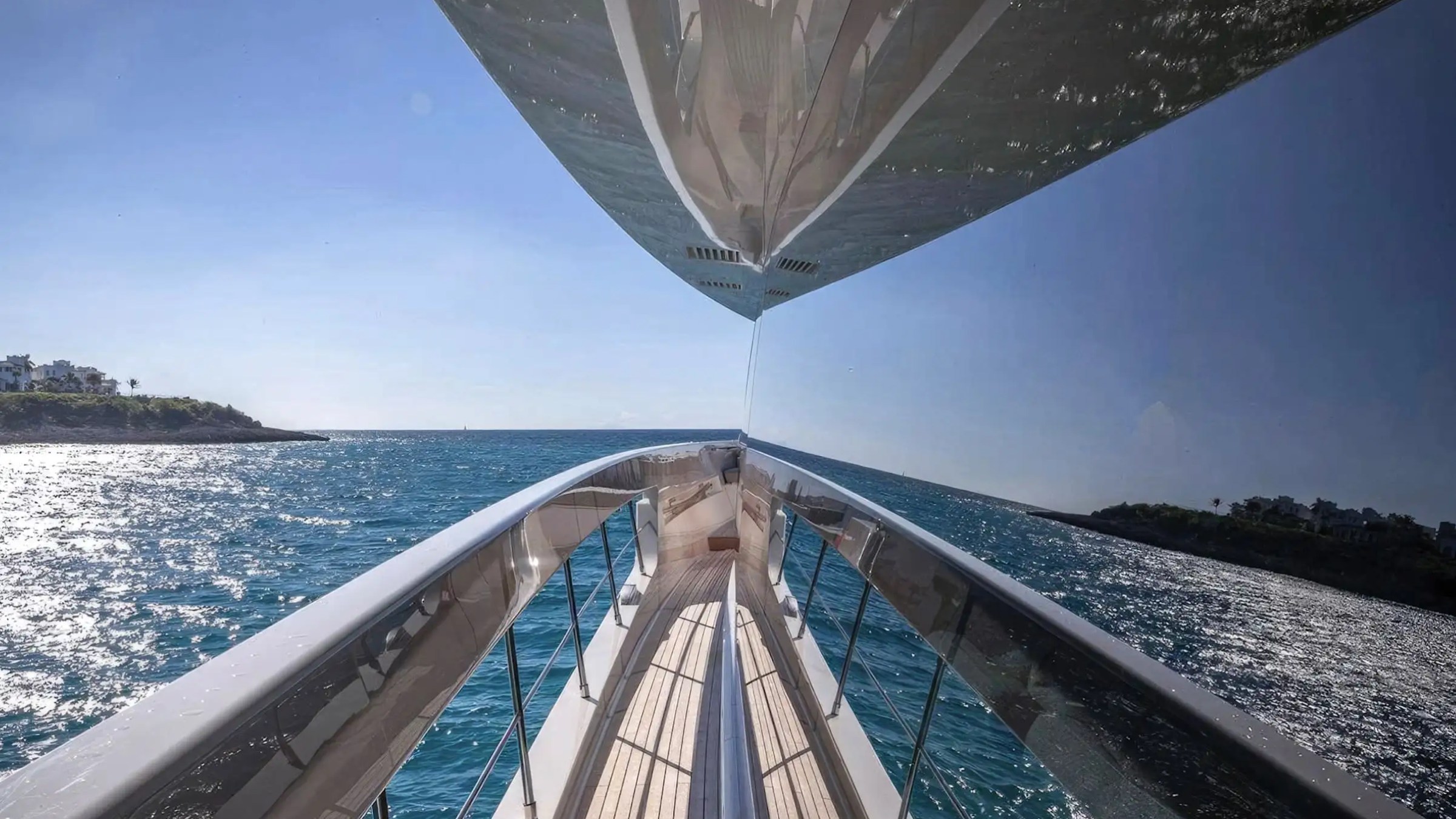 Reflection of sky and sea on a yacht window, with coastline in the distance.