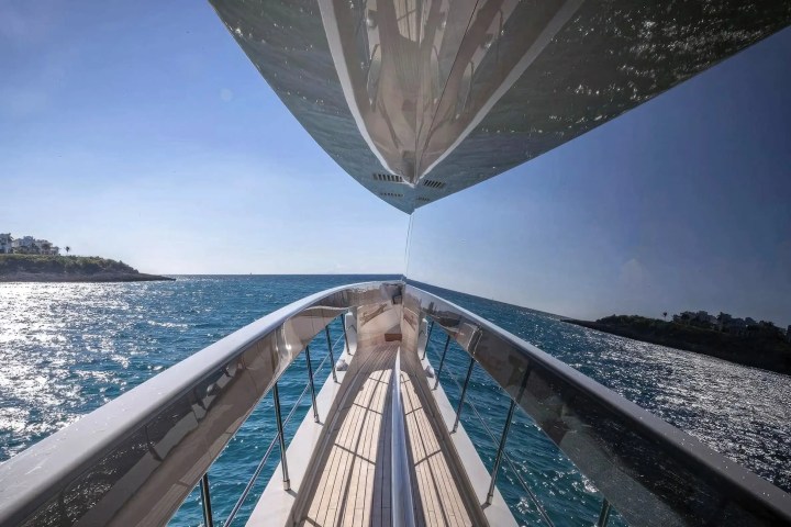 Reflection of sky and sea on a yacht window, with coastline in the distance.