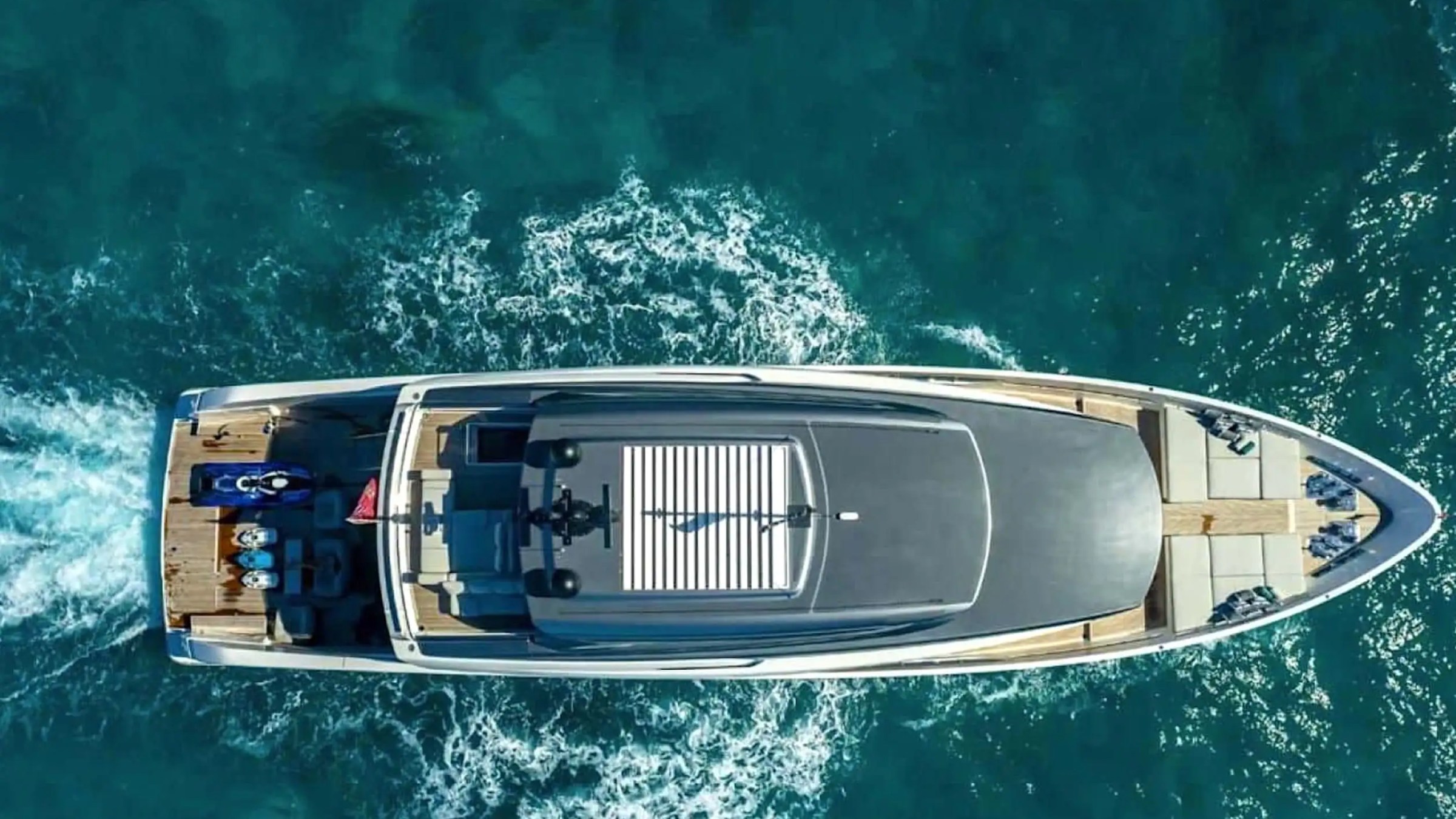 Aerial view of a large yacht cruising on clear blue water.