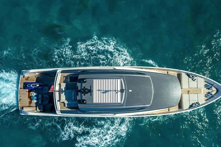 Aerial view of a large yacht cruising on clear blue water.