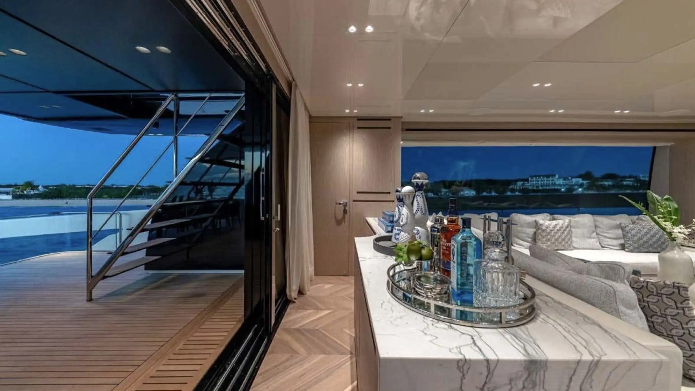 Luxurious yacht interior with a bar, seating area, and outdoor view at dusk.