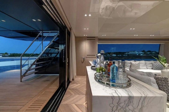 Luxurious yacht interior with a bar, seating area, and outdoor view at dusk.