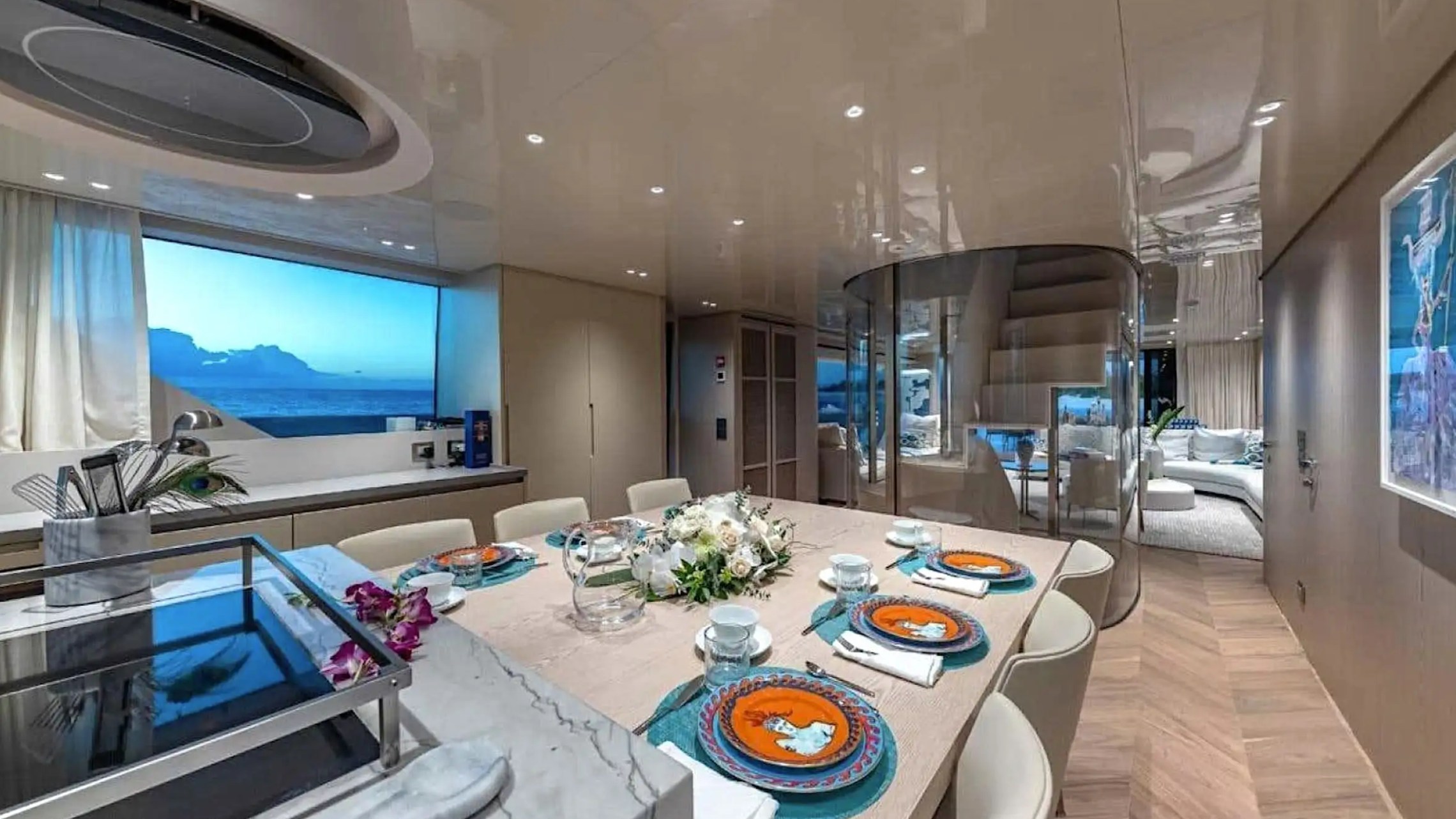 Luxurious yacht interior with set dining table, large window, and modern decor.
