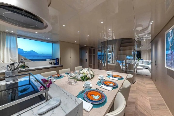 Luxurious yacht interior with set dining table, large window, and modern decor.