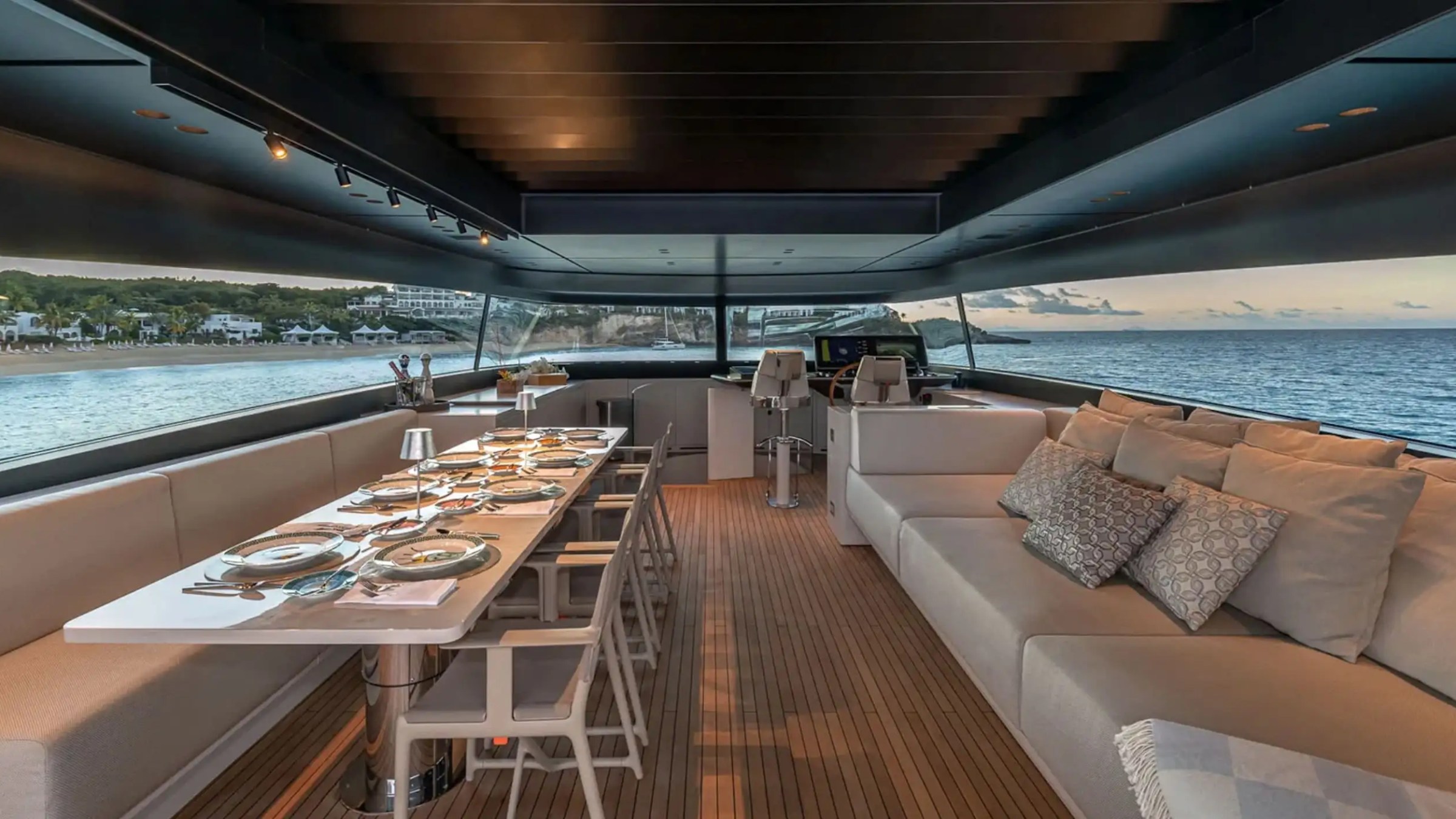 Luxurious yacht interior with dining table set for a meal, sofas, and ocean view.