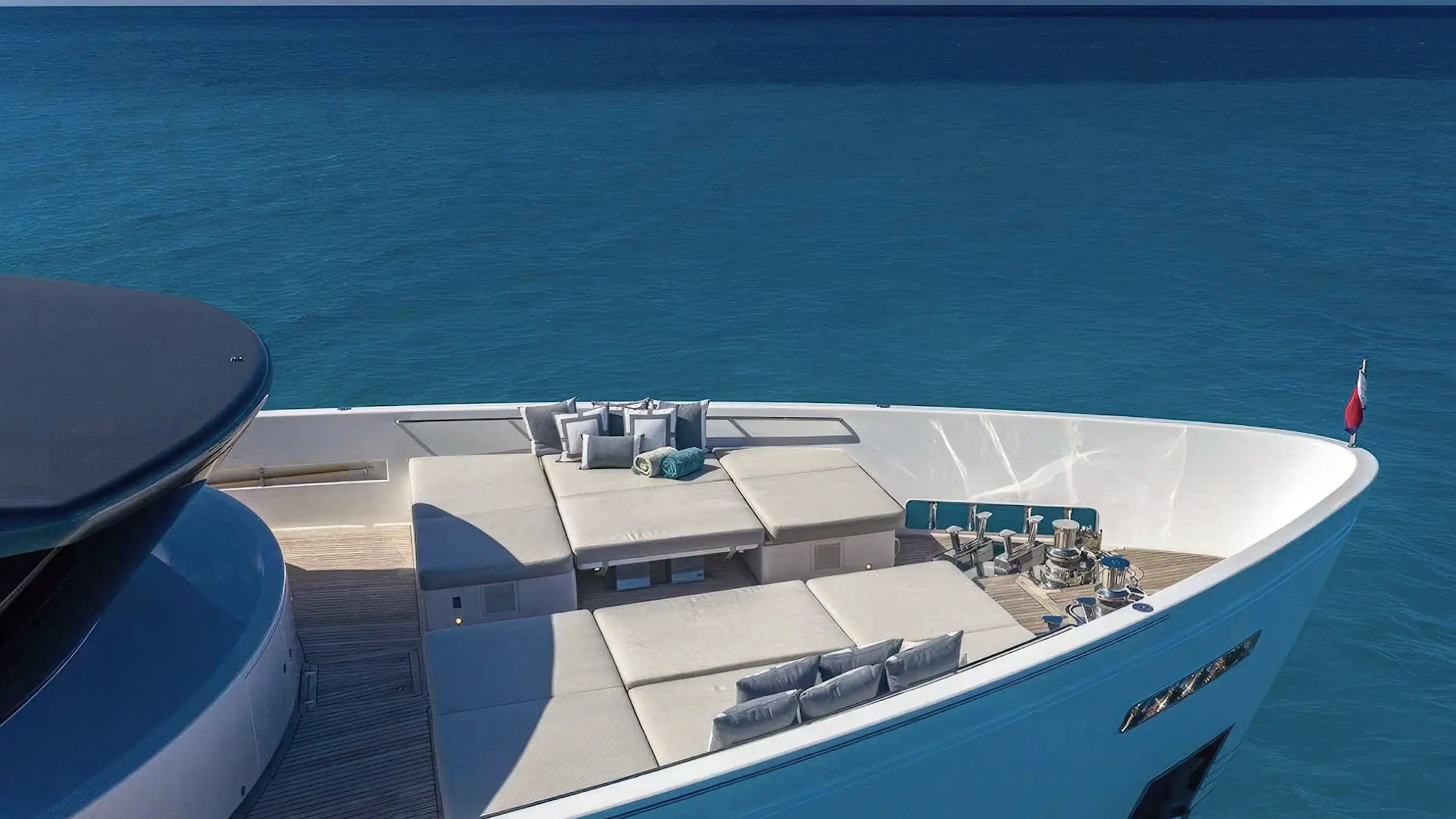 Luxury yacht bow with sun loungers and cushions, surrounded by clear blue ocean