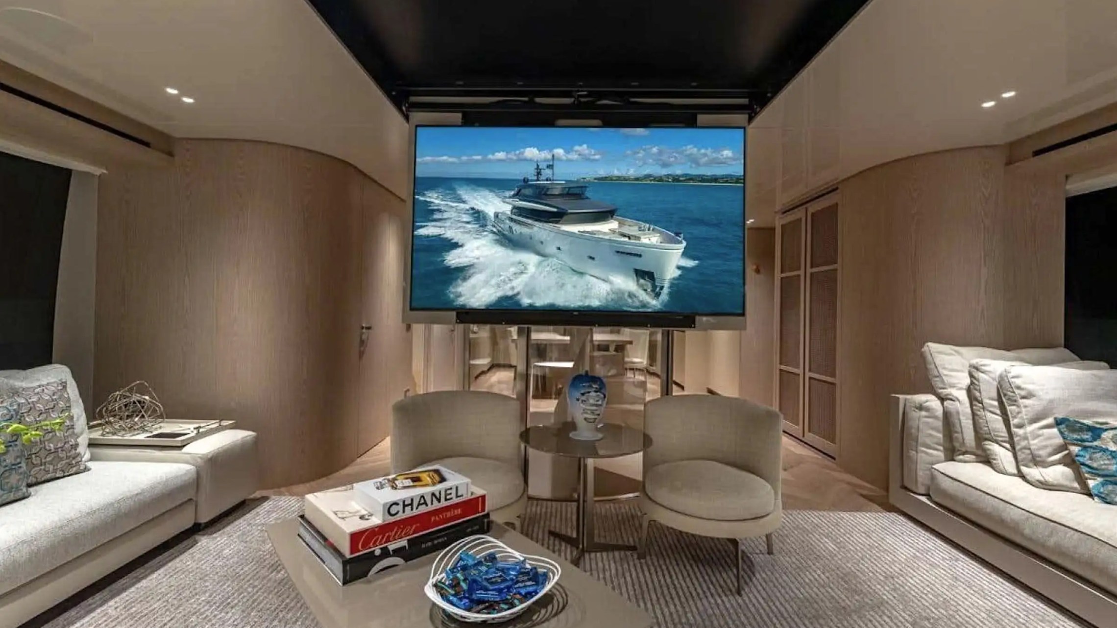 Luxurious yacht interior with a large TV, modern seating, and decor books.