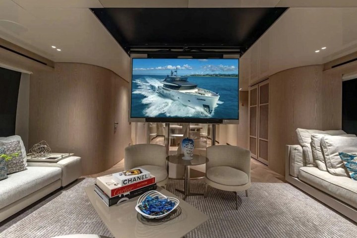Luxurious yacht interior with a large TV, modern seating, and decor books.